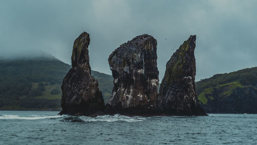 Panoramic view of rock formation in sea against sky