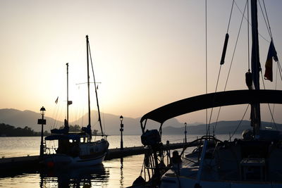 Boats moored in harbor at sunset