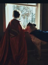 Rear view of man and woman with dog on window