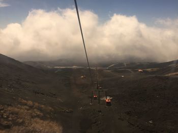 Overhead cable car over mountains against sky