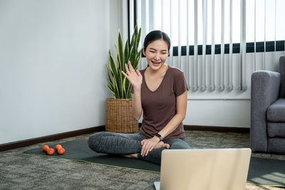 Young woman using laptop while sitting on sofa at home