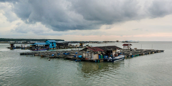 Boats in sea against cloudy sky