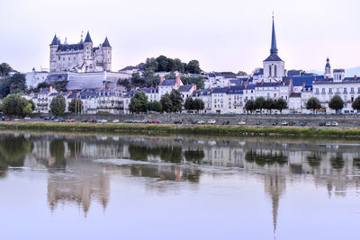 Views of the city of saumur from the riverbank at dusk, with the castle in the background. 