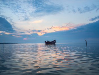 Boat in sea against sky during sunset