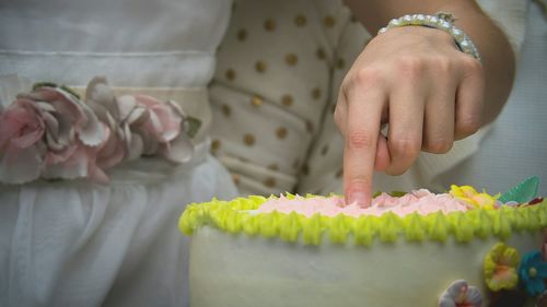 Close-up of hand touching cake on table