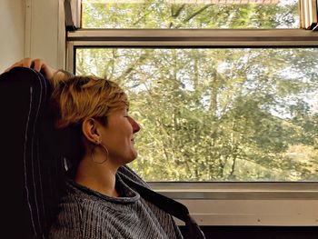 Portrait of young woman looking through window