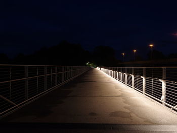 Narrow footbridge along trees at night