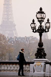 Full length of woman standing on bridge against eiffel tower in city