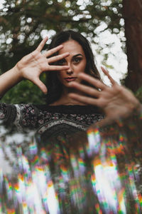 Portrait of woman holding umbrella against tree