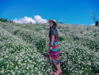 Portrait of smiling young woman standing on land against sky