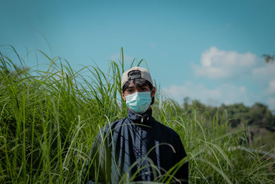 Rear view of man standing against sky and tall grass. 