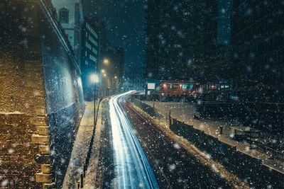 Illuminated railroad tracks in city during winter