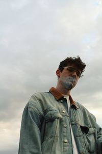 Low angle view of man wearing sunglasses standing against sky