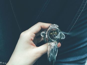 Midsection of person holding smoking pipe