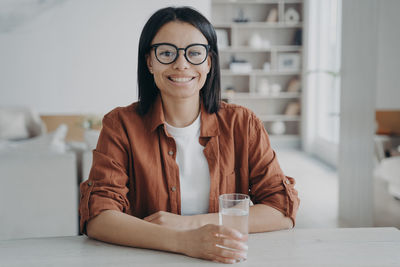 Portrait of young woman using mobile phone while sitting on table