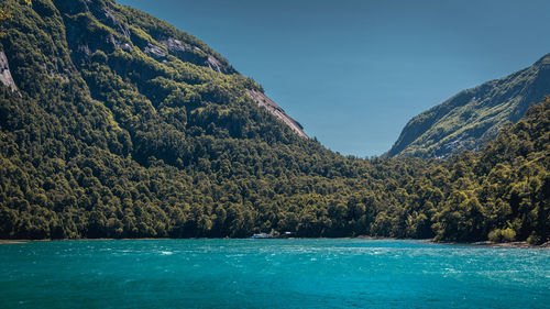 Scenic view of sea by mountain against sky