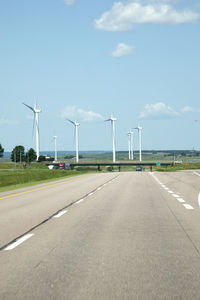 Wind turbines on road against sky