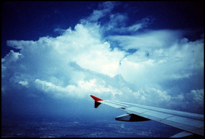 Airplane wing against cloudy sky