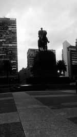 Statue in front of building against cloudy sky