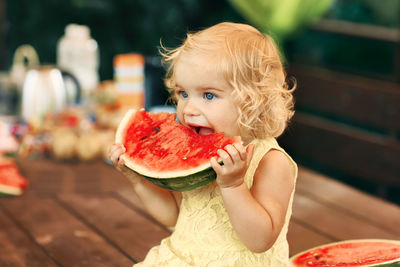 Girl eating watermelon on table