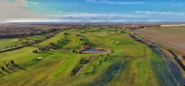 Scenic view of golf course field against sky