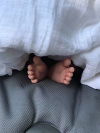 Low section of baby sitting on bed at home