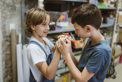 Curious male and female students examining electric motor at workshop in school