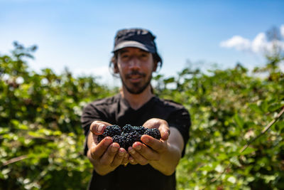 Portrait of man holding fruit against plants