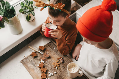 Children drink cocoa with marshmallows and christmas gingerbread man on a wooden background. 
