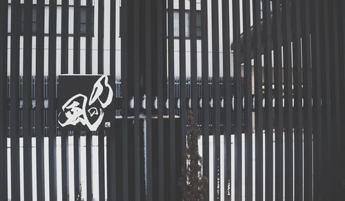 Close-up of sign on fence against building