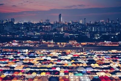 High angle view of illuminated city buildings against sky during sunset