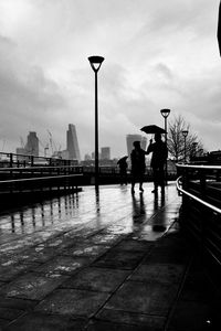People walking on city street against cloudy sky