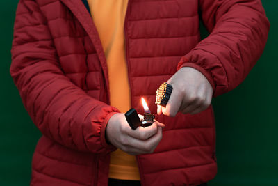 Midsection of man holding lit candles