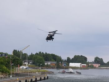 Helicopter flying over river against sky