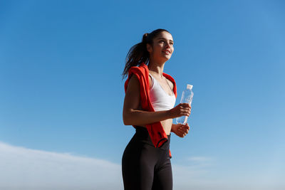 Full length of woman standing against blue sky