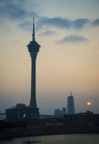 Tower by building against sky during sunset