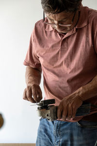 Man using angle grinder, cutting a screw, friction sparks, clamping screw with tweezers concentratio