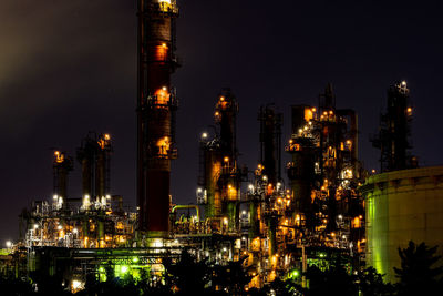 Illuminated factory against sky at night