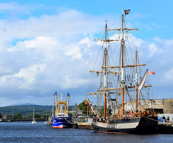 Sailboats moored at harbor against sky