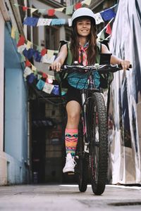Smiling woman riding bicycle on alley