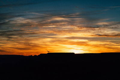 Silhouette landscape against orange sky