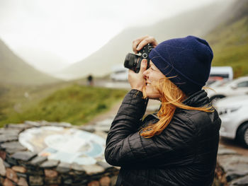 Woman photographing three sisters of glencoe, on a wet day