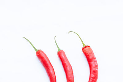 Close-up of red chili peppers over white background