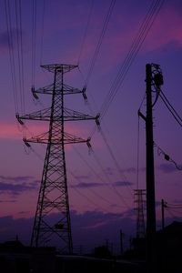 Low angle view of silhouette electricity pylon against sky at sunset