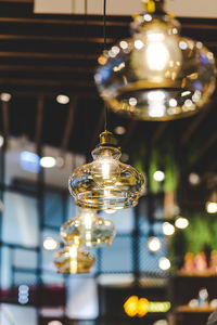 Close-up of illuminated light bulb hanging from ceiling