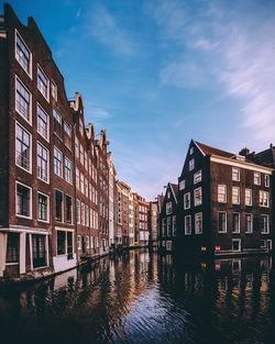 Canal by building against sky