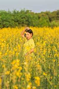 Woman standing by yellow flowers on field