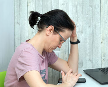 Side view of woman using phone at table