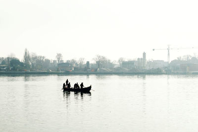 People on boat in lake against clear sky