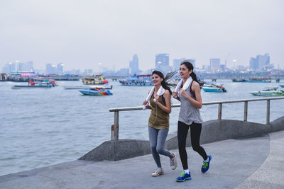 Woman standing on shore against city skyline